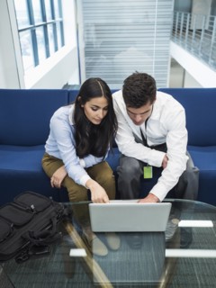 Business people using laptop in office lobby