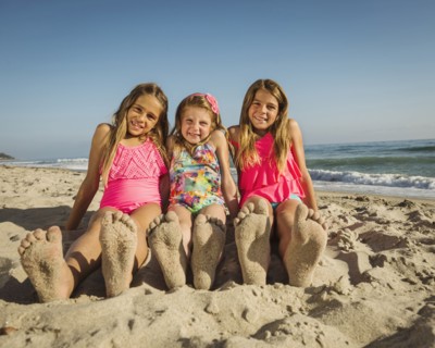 Caucasian sisters with sandy feet on beach