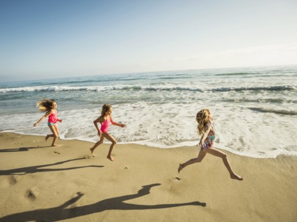 Caucasian sisters running on beach