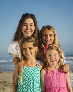 Caucasian mother and daughters smiling on beach