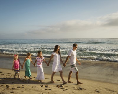 Caucasian family holding hands on beach