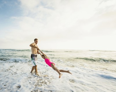 Caucasian father and daughter playing in waves on beach