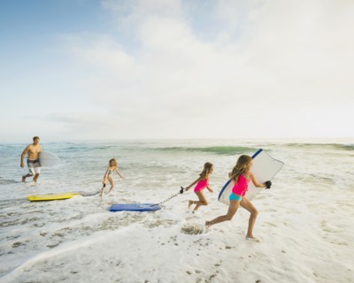 Caucasian father and daughters playing in waves on beach