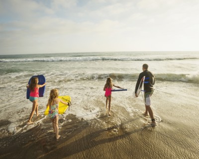 Caucasian father and daughters playing in waves on beach