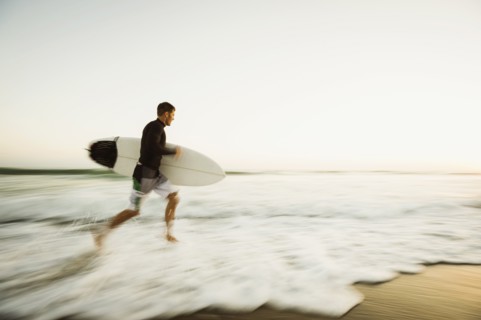 Caucasian man carrying surfboard on beach