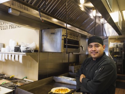 Hispanic chef smiling in kitchen