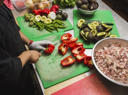 Hispanic chef cutting vegetables in kitchen
