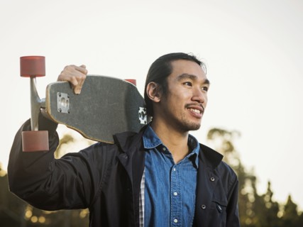 Chinese man carrying skateboard outdoors