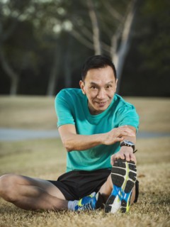 Older Chinese man stretching in park