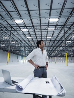 Indian architect standing with hands on hips in empty warehouse