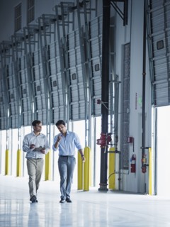 Businessmen walking with clipboard near open loading dock doors