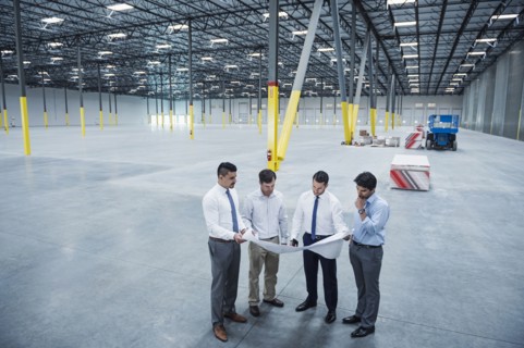 Architects examining blueprint in empty warehouse