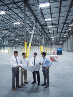 Architects examining blueprint in empty warehouse