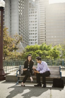 Chinese business people using technology on city bench