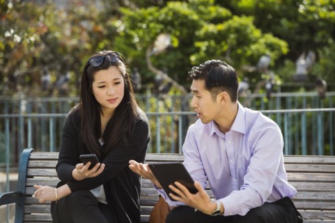 Chinese business people using technology on city bench