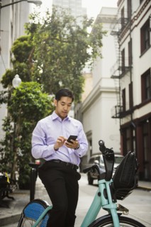 Chinese businessman on bicycle texting on cell phone