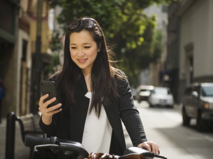 Chinese businesswoman on bicycle texting on cell phone