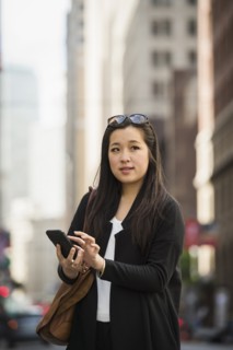 Chinese businesswoman texting on cell phone in city