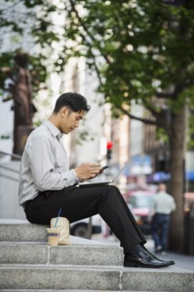 Chinese businessman texting on cell phone during lunch in city