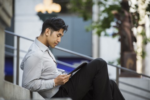 Chinese businessman reading digital tablet on staircase