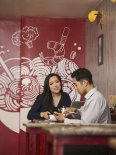 Chinese business people texting on cell phone in restaurant