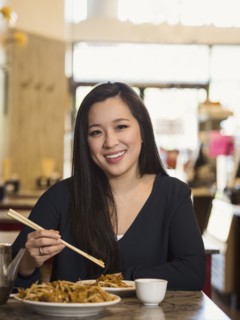 Chinese woman eating with chopsticks in restaurant
