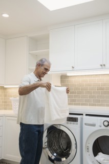 Caucasian man folding towel in modern laundry room