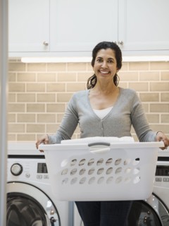 Hispanic woman carrying basket in modern laundry room