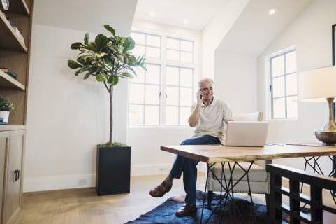 Caucasian man talking on cell phone in home office