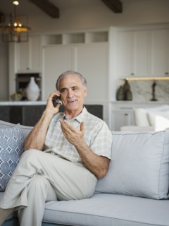 Caucasian man sitting on sofa talking on cell phone