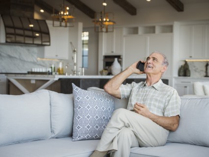 Caucasian man sitting on sofa talking on cell phone
