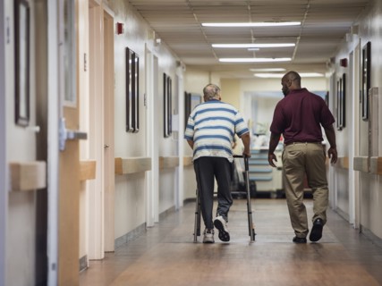 Nurse walking with patient using walker