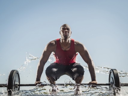 Water spraying on black man preparing for lifting barbell