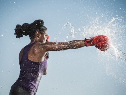Water spraying on black woman boxing