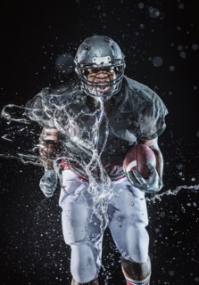 Water splashing on black football player running