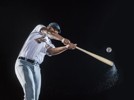 Water splashing from swinging bat of black baseball player