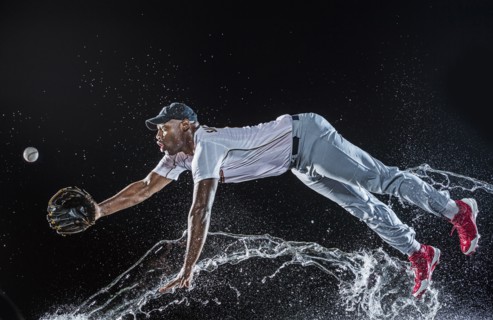 Water splashing on diving black baseball player