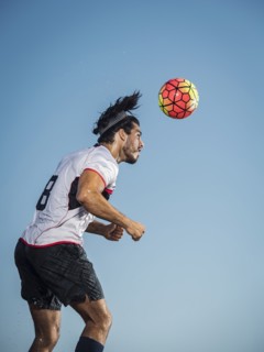 Hispanic man heading soccer ball