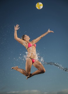 Water splashing on Caucasian woman jumping to volleyball