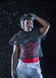 Water splashing on Black football player lifting helmet