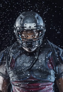 Water splashing on Black football player wearing helmet