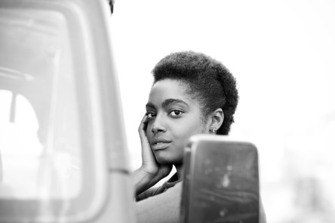 African American woman leaning on car