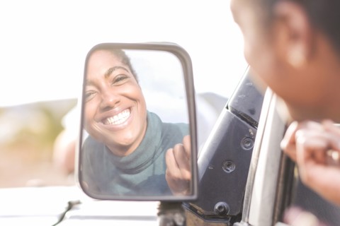 Reflection of African American woman in car mirror