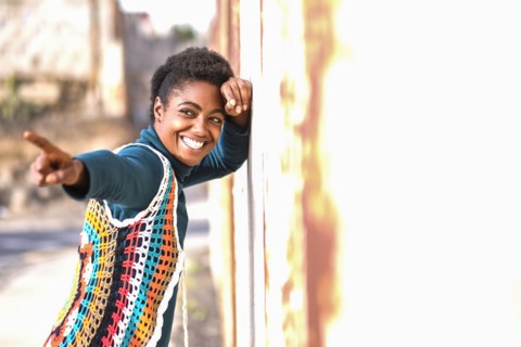 Smiling African American woman leaning on wall and pointing finger