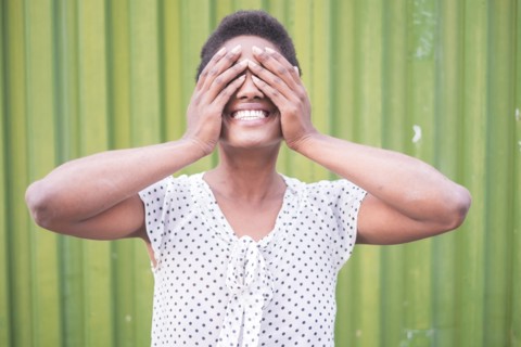 Smiling African American woman covering eyes