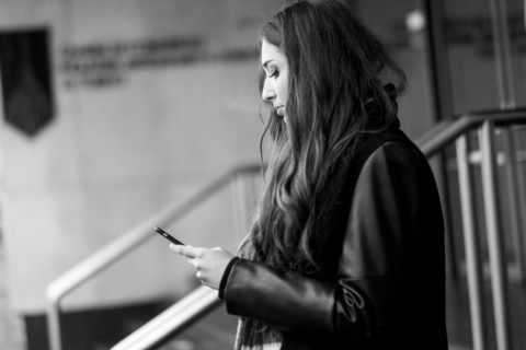 Serious Caucasian woman texting on cell phone