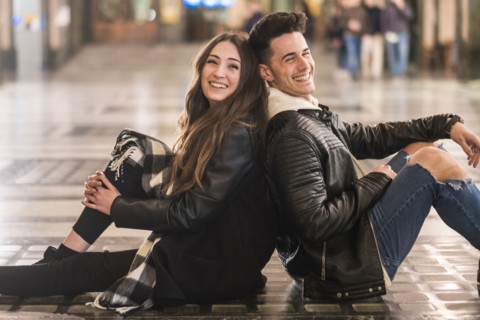 Caucasian couple sitting back to back on lobby floor