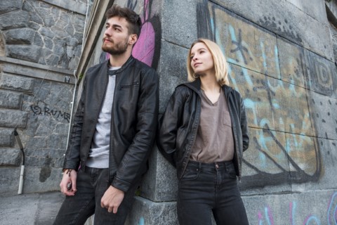 Caucasian couple leaning on wall with graffiti