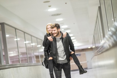 Caucasian man carrying woman piggyback in corridor