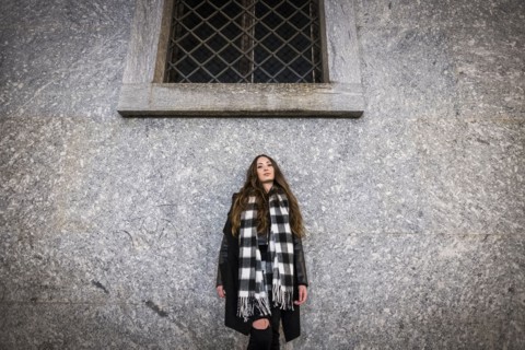 Serious Caucasian woman leaning on wall under window
